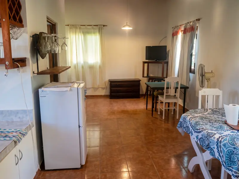 Cocina y mesa de la cabaña para dos, con heladera y televisor